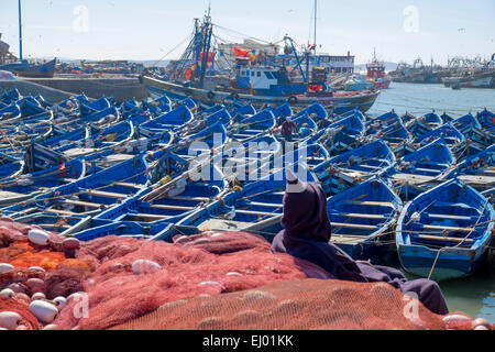 Barche da pesca e uomo in abito tradizionale nel porto di Essaouira, Marocco, Africa del Nord Foto Stock