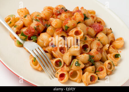 Gomiti gomito gusci di pasta si lancia in arrabbiata pomodoro aglio e peperoncino salsa e servite con prezzemolo tritato Foto Stock