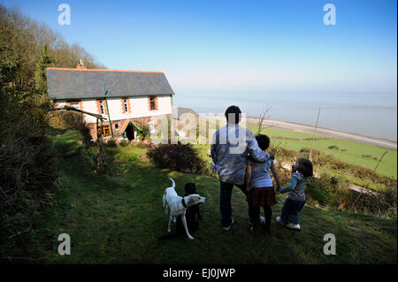 Un padre e i suoi bambini Vista la loro casa costiera nel Devon, Regno Unito Foto Stock