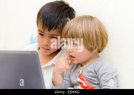 Due bambini staring al laptop Foto Stock