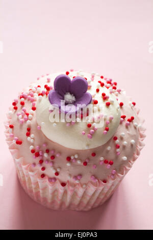 Tesco con amore di fragole e panna tortina con fiore in cima isolata su sfondo rosa Foto Stock