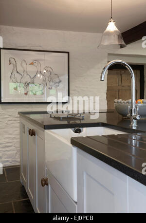 Un bianco in stile country cucina in una casa colonica nel Regno Unito con muri in pietra e un dissipatore di Belfast. Foto Stock