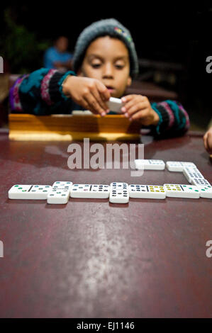 Vista verticale di un giovane ragazzo in un gioco di domino che viene riprodotto in Cuba. Foto Stock