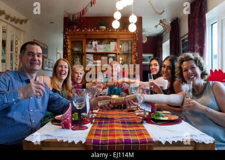 Vista orizzontale di tre generazioni di una famiglia tirare petardi durante la cena di Natale. Foto Stock