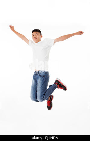 Ragazzo adolescente jumping in mid-aria con le braccia aperte Foto Stock