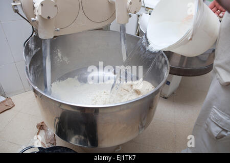 Aggiunta di acqua per robot da cucina per impastare la pasta per pane. Processo di fabbricazione del pane in spagnolo Foto Stock