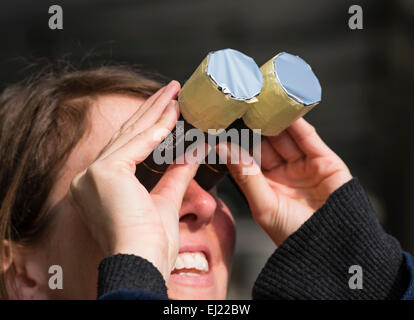 Zurigo, Svizzera. 20 Mar, 2015. Una giovane donna sta guardando attraverso un binocolo con un self-made filtro per proteggere i suoi occhi mentre si guarda il 2015 Parziale eclissi solare a Zurigo. Credito: thamerpic/Alamy Live News Foto Stock