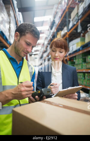 Il lavoratore e il manager pacchetto di scansione in magazzino Foto Stock