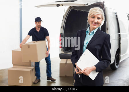 Driver di consegna imballaggio il suo furgone con manager sorridente Foto Stock