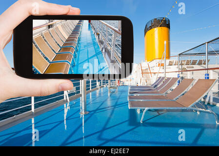 Concetto di viaggio - tourist scatta foto di prendere il sole sedie sul ponte superiore della nave da crociera sullo smartphone, Foto Stock