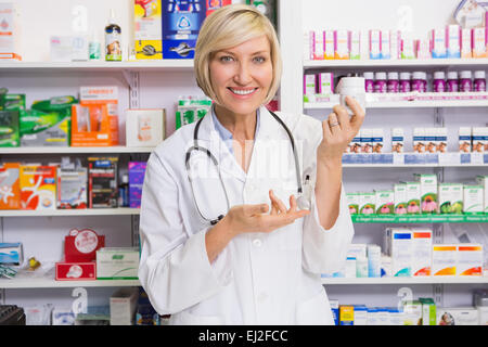 Sorridente al farmacista che mostra farmaco alla fotocamera Foto Stock