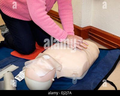 Donna primo soccorso praticando un massaggio cardiaco le compressioni toraciche su un manichino manichino durante un St John Ambulance corso di primo soccorso. Regno Unito Foto Stock