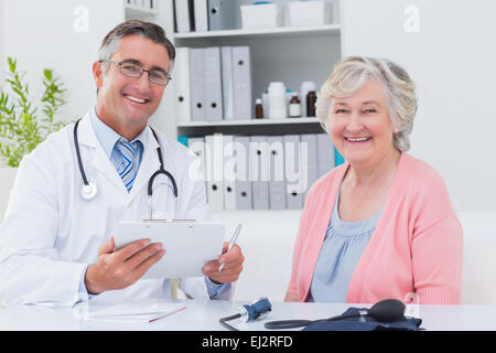 Medico tenendo appunti durante la seduta con paziente senior Foto Stock
