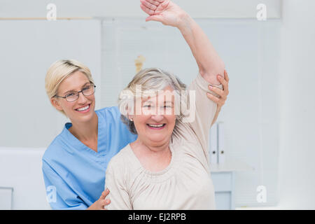 Paziente senior di essere assistito da un infermiere nel braccio di sollevamento Foto Stock