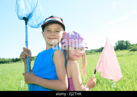 Un bambino che prova a catturare alcuni butterfly con net. Foto Stock