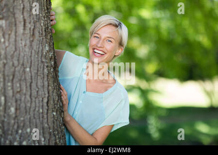 Bella bionda nascosto dietro un albero Foto Stock