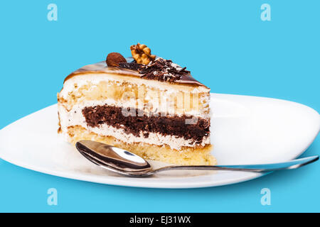 Pezzo di torta con uno strato di cioccolato su uno sfondo blu Foto Stock