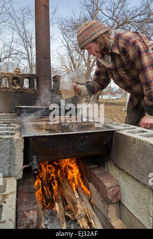 Detroit, Michigan - Kieran Neal bolle sap da zucchero alberi di acero su un fuoco di legno per fare lo sciroppo d'acero. Foto Stock