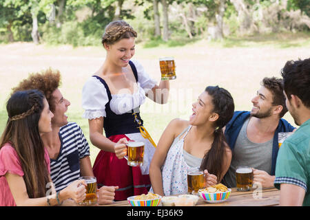 Bella ragazza oktoberfest che servono gli amici Foto Stock