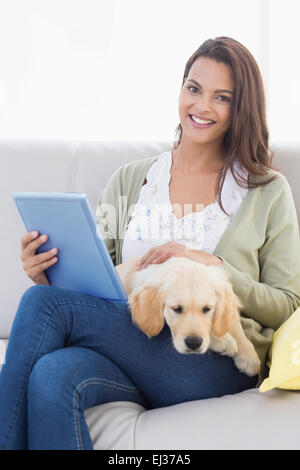 Donna con cane usando computer tablet sul divano Foto Stock