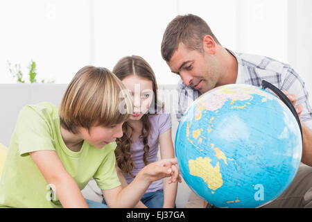 I bambini ad esplorare globe seduti con il padre Foto Stock