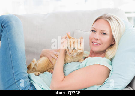 Donna abbracciando cat mentre sdraiato sul divano Foto Stock