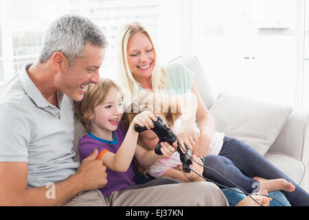 I genitori guardare i bambini giocare video gioco Foto Stock
