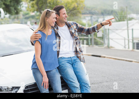 Coppia sorridente appoggiato sul cofano Foto Stock