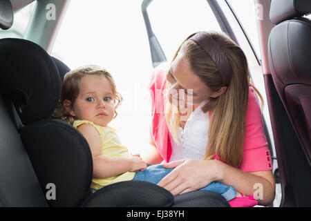 Madre che fissano il suo bambino nel seggiolino per auto Foto Stock