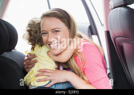 Madre che fissano il suo bambino nel seggiolino per auto Foto Stock