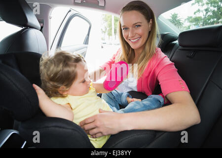 Madre che fissano il suo bambino nel seggiolino per auto Foto Stock