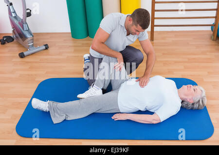 Il trainer lavora con il senior donna sul tappeto di esercizio Foto Stock