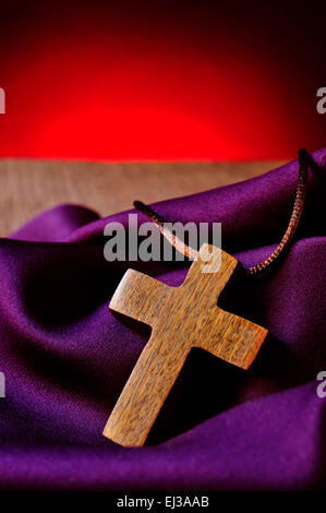 Un semplice di legno una Croce Cristiana su di un drappo di porpora Foto Stock