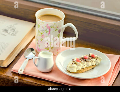 La prima colazione con caffè, latte e una fetta di torta con cuori servita sul davanzale, tonica Foto Stock