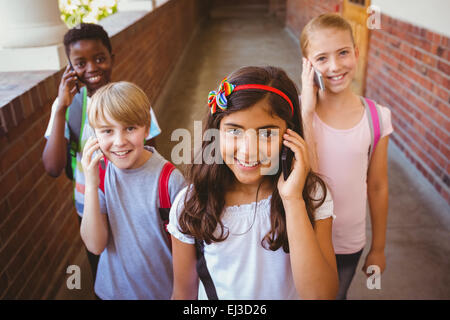 Ragazzi delle scuole tramite telefoni cellulari nel corridoio della scuola Foto Stock