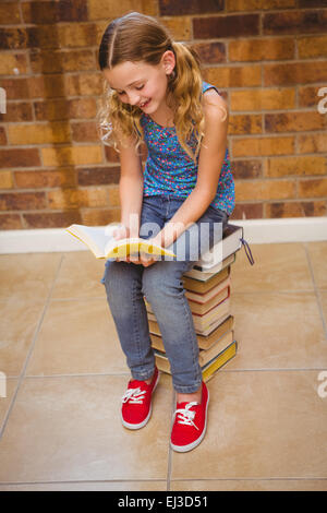 Carino bambina la lettura di libro in biblioteca Foto Stock