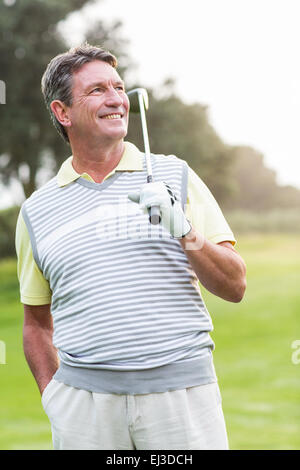 Il Golfer in piedi ed oscillante il suo club sorridente in telecamera Foto Stock