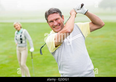 Felice golfista off di rinvio con il partner dietro di lui Foto Stock