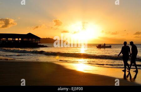 Giovane a piedi lungo la spiaggia al tramonto Foto Stock