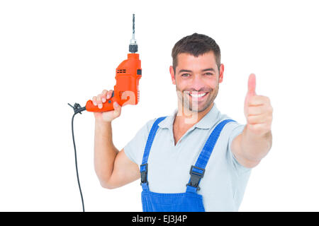 Sorridente aggiustatore con macchina seminatrice gesticolando pollice in alto Foto Stock