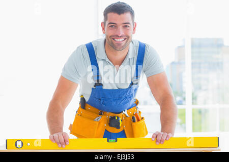 Sorridente tuttofare utilizzando la livella in office Foto Stock