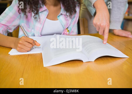 Studente ottenere aiuto dal tutor in biblioteca Foto Stock