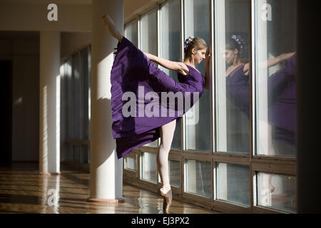 Graziosa ballerina dancing in un abito viola da gamba sollevato in alto, st Foto Stock