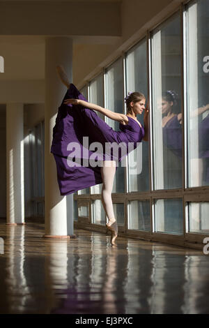 Graziosa ballerina dancing in un abito viola da gamba sollevato in alto, st Foto Stock