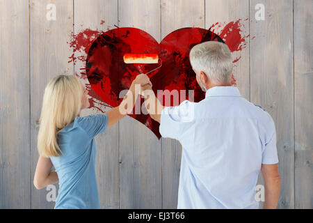 Immagine composita della coppia felice muro dipinto con il rullo Foto Stock