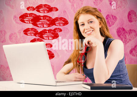 Immagine composita di pretty redhead lavorando sul computer portatile Foto Stock