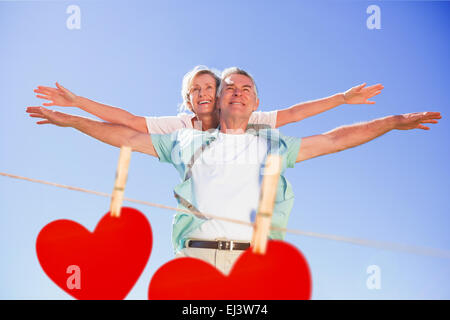 Immagine composita di felice senior uomo dando il suo partner un piggy back Foto Stock