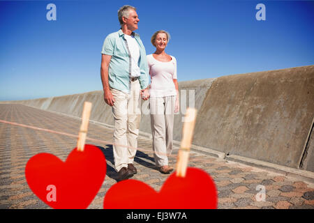 Immagine composita di felice coppia senior camminando sul molo Foto Stock