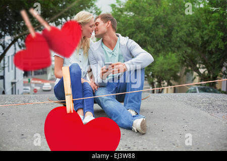 Immagine composita di hip coppia giovane seduto su skateboard kissing Foto Stock