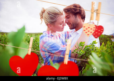 Immagine composita della coppia sorridente abbracciando fuori tra le boccole Foto Stock